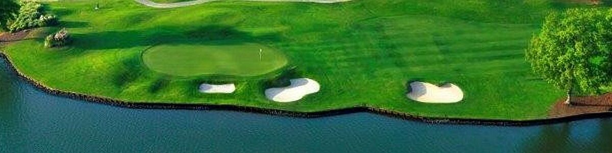 A golf green with a sand bunker near a water hazard.