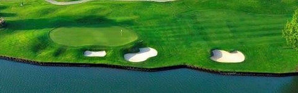 A golf green with a sand bunker near a water hazard.